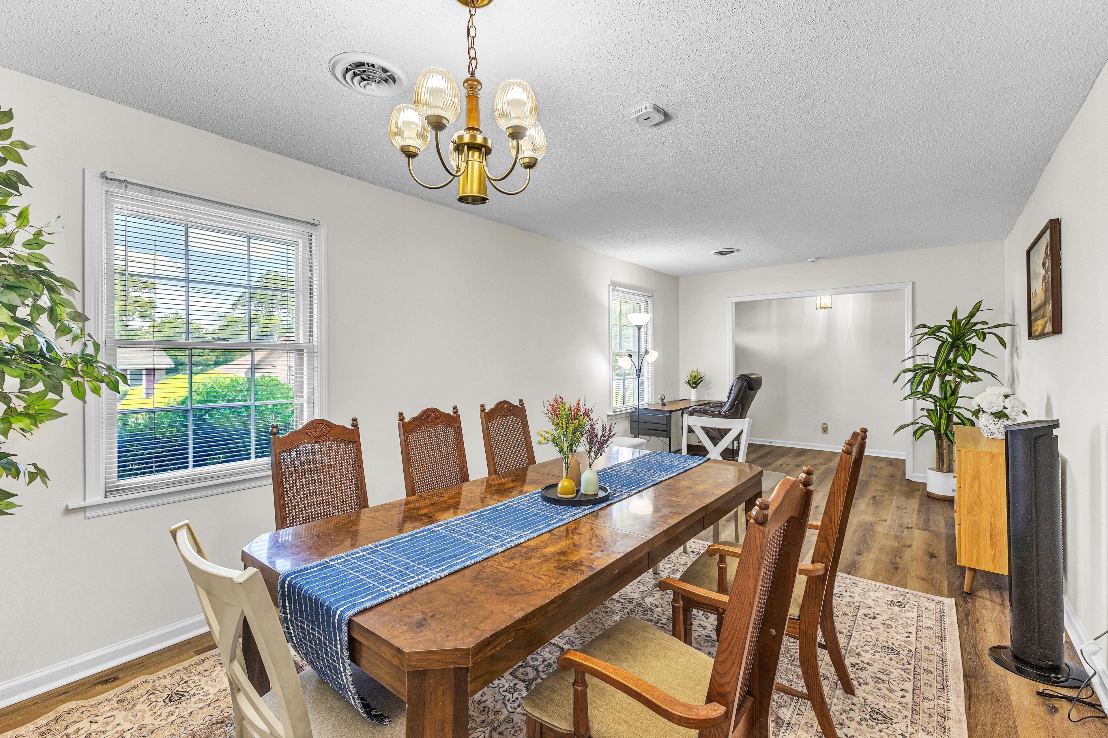 A dining room with a wooden table, chairs, and a chandelier.