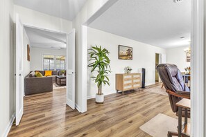 A spacious living area with hardwood flooring, a sofa, a coffee table, a potted plant, a painting, and a leather armchair. - Spacious 4-bedroom house with large backyard near Maxwell AFB (Montgomery)
