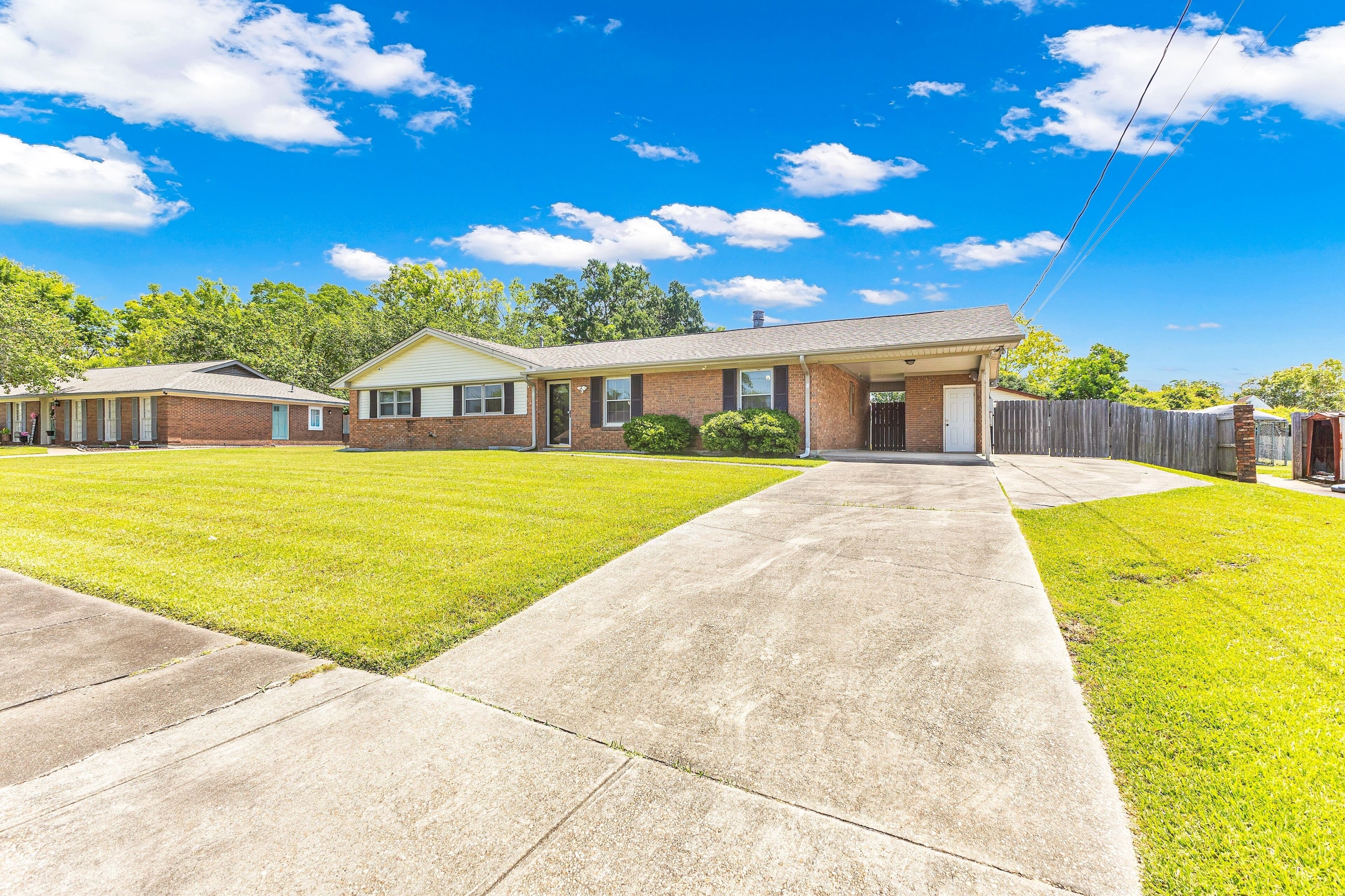 A residential property with a two-story house, a front lawn, and a wooden fence.