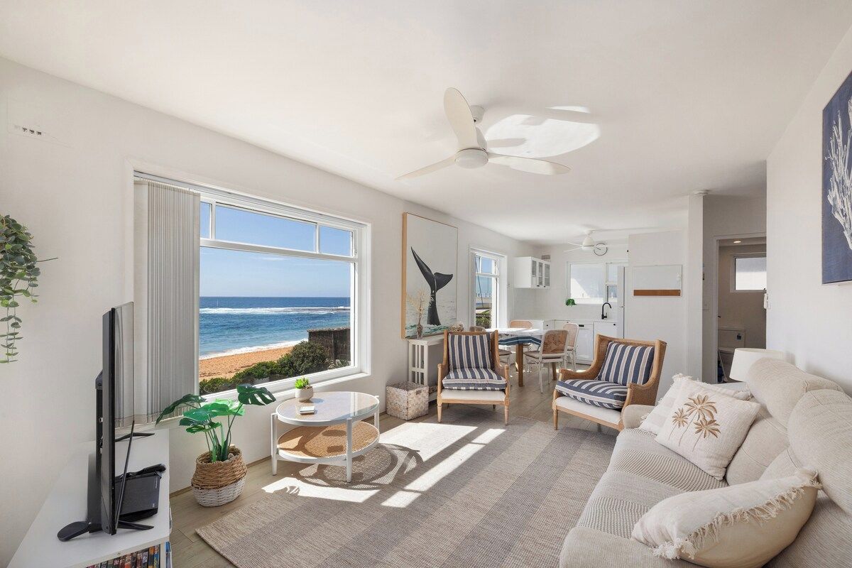 Ein Wohnzimmer mit Meerblick, einem Deckenventilator und einem Sofa.