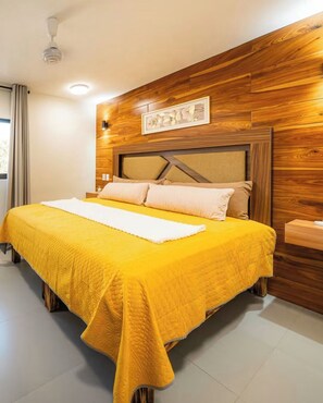 Un letto con una coperta gialla, una testiera in legno e un quadro appeso al muro.