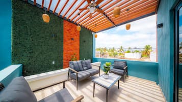 A modern outdoor seating area with a green wall, a brick wall, and a view of the surrounding landscape.
