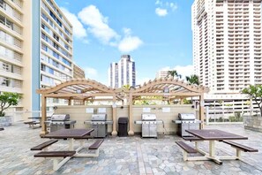 Ein Terrassenbereich im Freien mit Grillanlagen und Picknicktischen.