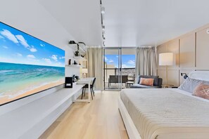 Ein modernes Hotelzimmer mit großem Fernseher, einem Bett, einem Schreibtisch und einem Balkon mit Blick auf die Stadt.