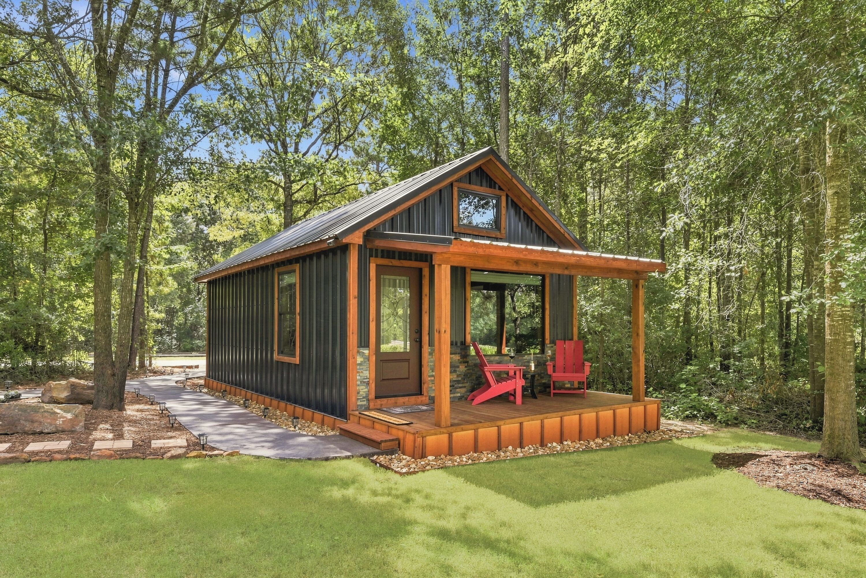 Eine kleine Holzhütte mit Veranda, Tür und Fenster.