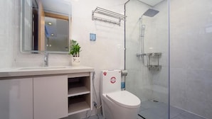A modern bathroom with a glass shower enclosure, a white toilet, and a sink with a mirror above it. - HSuites Riverside Hotel & Apartment  (An Hai)