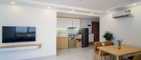A modern kitchen with built-in appliances, a dining area with a table and chairs, and a flat-screen TV mounted on the wall.