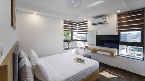 A modern bedroom with a bed, a window, a built-in TV, and a ceiling light fixture. - HSuites Riverside Hotel & Apartment  (An Hai)