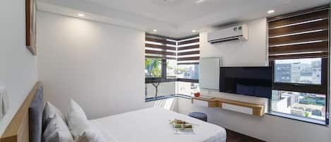 A modern bedroom with a bed, a window, a built-in TV, and a ceiling light fixture.