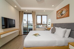 A hotel room with a bed, a TV, a window with curtains, and a city view.