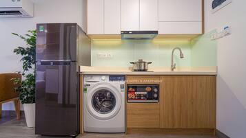 Una cocina compacta equipada con un refrigerador, lavadora y un lavamanos.