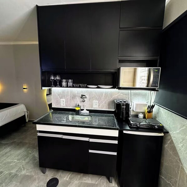 A compact kitchen with a microwave, sink, and a coffee maker.