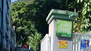 Een poort met een groen bord waarop een postbus, een parkeersignaal en een QR-code voor een mobiele app staan aangegeven.
