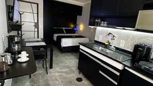 Een compacte hotelkamer met een kitchenette, een bed, een kleine eethoek en een badkamer.