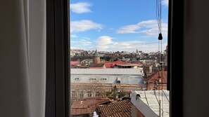 A view of a cityscape through a window, including buildings and a church tower. - Mikado Lounge – 2BR by Freedom Square with Fireplace (T'bilisi)