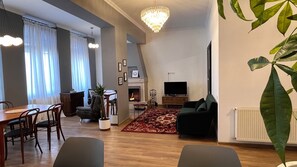 A modern living room with a fireplace, a dining area, and a television. - Mikado Lounge – 2BR by Freedom Square with Fireplace (T'bilisi)