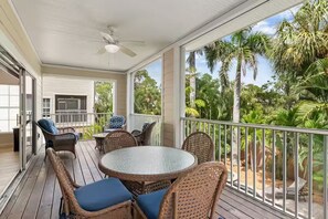 A covered outdoor area with wicker furniture, a round table, and a ceiling fan. - NEW! Steps to Beach, Hot Tub, Pool, Kid Friendly (Holmes Beach)