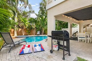 A backyard with a pool, a grill, and outdoor furniture. - NEW! Steps to Beach, Hot Tub, Pool, Kid Friendly (Holmes Beach)
