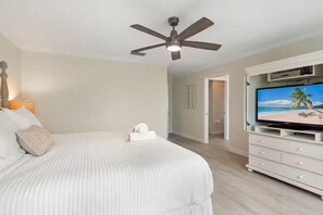 A bedroom with a bed, a ceiling fan, a television, and a dresser. - NEW! Steps to Beach, Hot Tub, Pool, Kid Friendly (Holmes Beach)