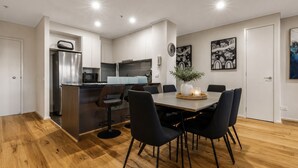 A modern kitchen with a central island, dining area with chairs, and artwork on the walls. - City Road Vista Southbank by Ready Set Stay (Southbank)