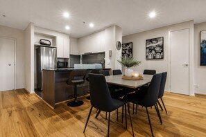 Una cocina moderna con una isla central, comedor con sillas y obras de arte en las paredes.