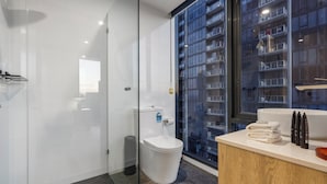 A modern bathroom with a glass shower enclosure, a white toilet, and a vanity with a sink and towel stack. - City Road Vista Southbank by Ready Set Stay (Southbank)