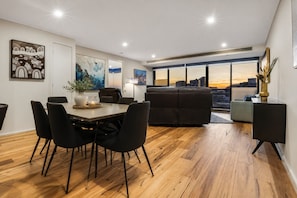 Ein modernes Wohnzimmer mit Essbereich, einer Couch und Blick auf die Stadtlandschaft.