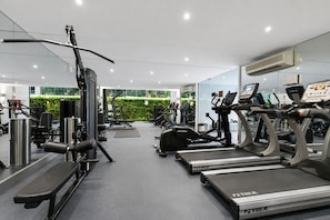 Ein Fitnessstudio mit Laufbändern, Kraftgeräten und einer Spiegelwand.