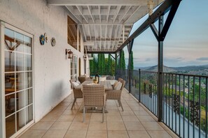Een terras buiten met een tafel, stoelen, een leuning en uitzicht op het landschap.