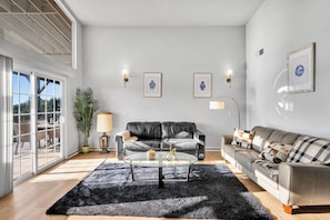 Un salon moderne avec une table basse en verre, des canapés en cuir et une grande fenêtre offrant une belle vue.