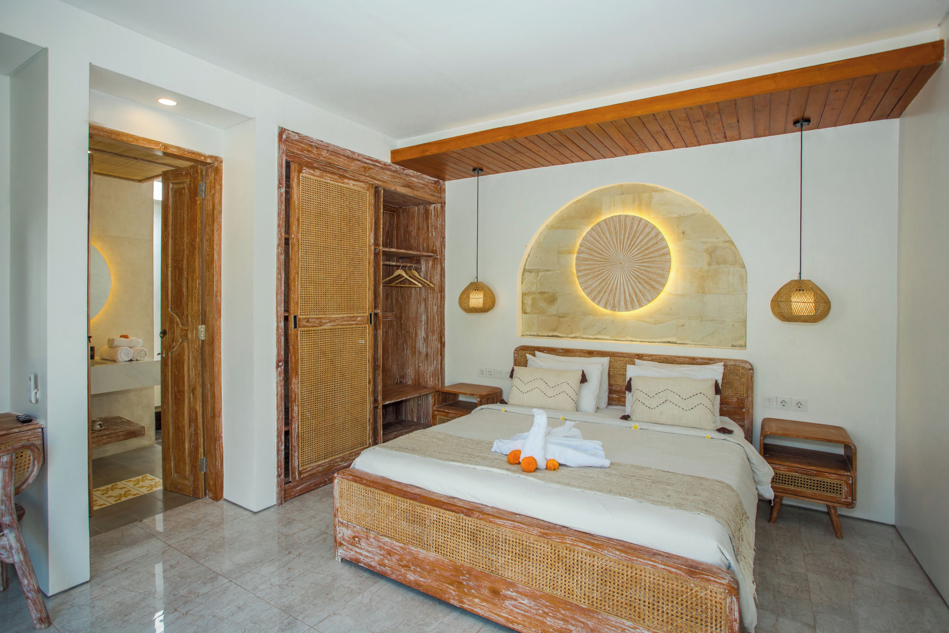 A bedroom with a large bed, wooden headboard, and a stone wall feature.