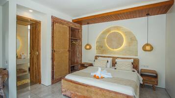 A bedroom with a large bed, wooden headboard, and a stone wall feature.