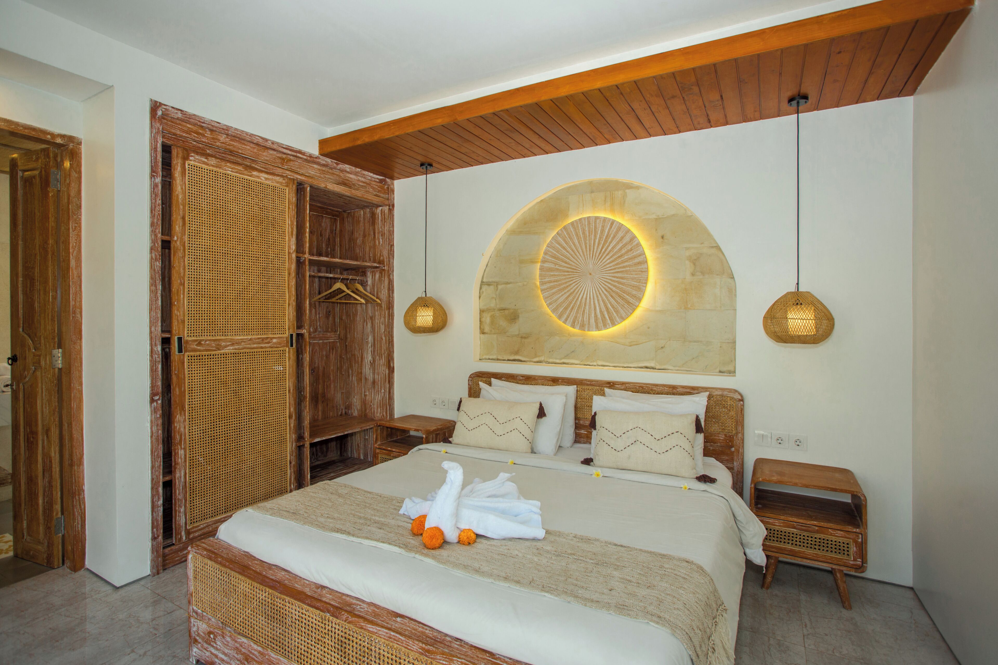 Un dormitorio con una cama grande, un armario de madera y una pared de piedra con una lámpara circular.