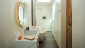 Un baño moderno con una bañera independiente, un espejo grande y una ducha.