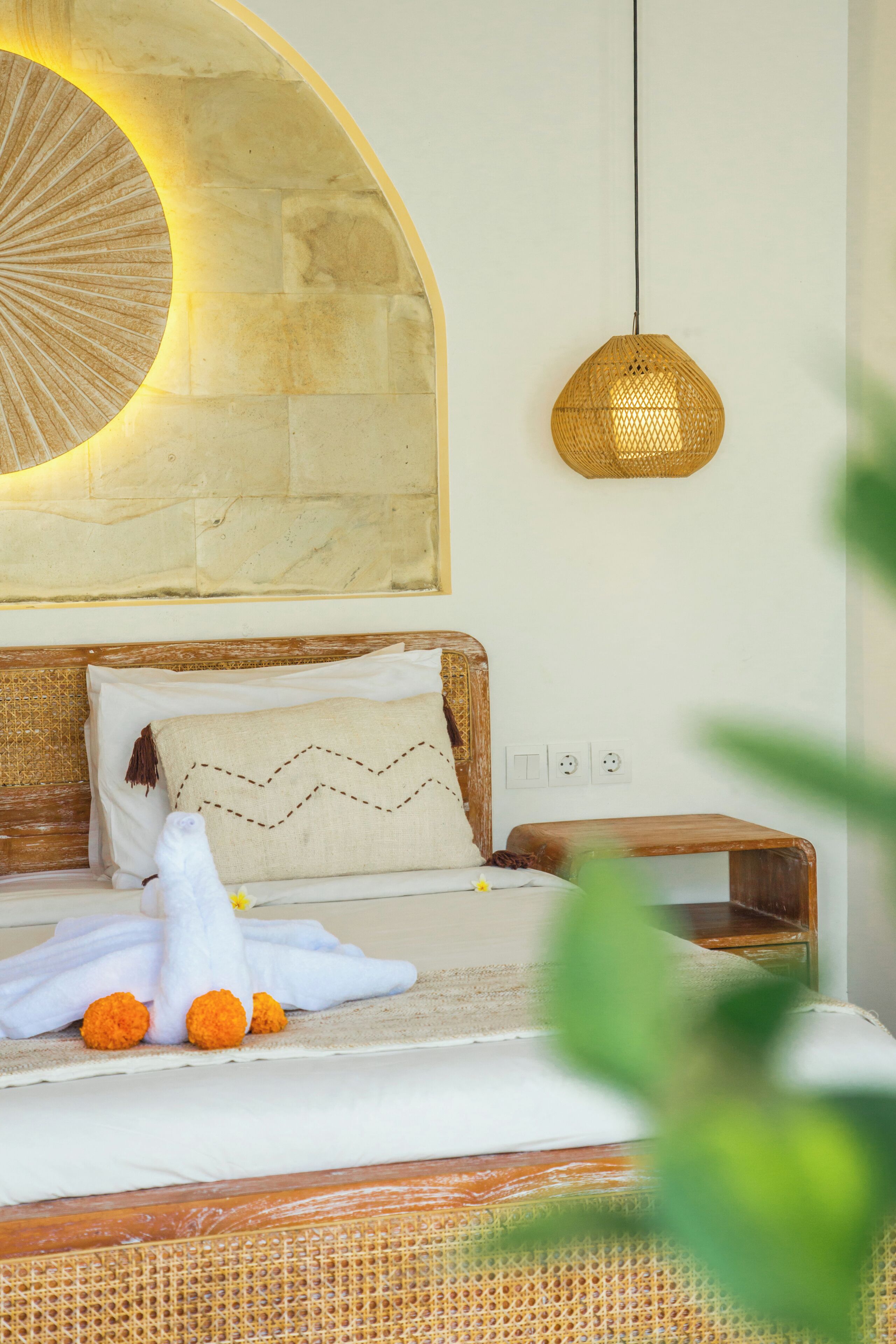 Una cama con una manta blanca, un cojín decorativo y un peluche.