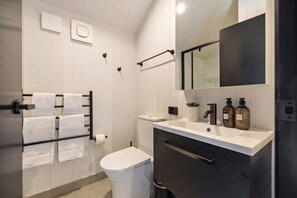 A modern bathroom with a toilet, sink, and towel rack.