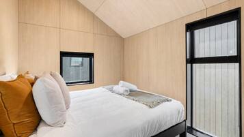 Une chambre moderne avec un lit, des oreillers, une fenêtre et une vue.