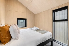 Ein modernes Schlafzimmer mit Bett, Kissen, einem Fenster und Blick.