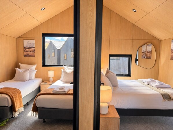 A hotel room with two beds, a wooden ceiling, and a view of a building outside.