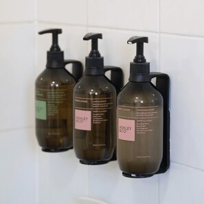 Three bottles of hair care products on a tiled wall.
