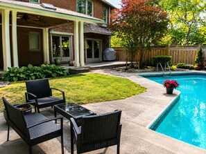 A backyard with a swimming pool, a covered patio area, and outdoor furniture. - Thornhill Luxury Retreat | Perfect for Families, Groups & Business Travellers (Markham)