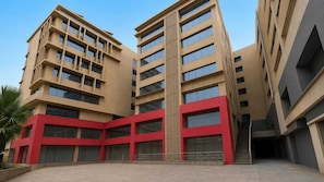 A multi-story building with a central courtyard, large windows, and a red accent wall. - Deluxe Hanspura Bus Terminal (Ahmedabad)