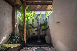 A tranquil indoor garden with a water feature, stone pathway, and lush greenery. - Rahasia Rumah Kerang Uluwatu (Pecatu)