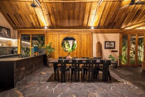 A dining area with a stone floor, wooden ceiling, and a round mirror on the wall. - Rahasia Rumah Kerang Uluwatu (Pecatu)