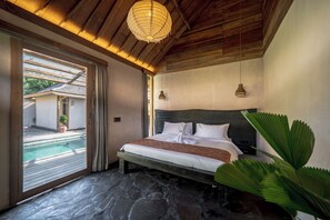 A bedroom with a stone floor, a bed with white linens, a wooden ceiling, and a view of a swimming pool. - Rahasia Rumah Kerang Uluwatu (Pecatu)