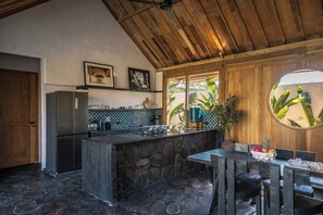 Een keuken met een stenen keukeneiland, een houten plafond en uitzicht op groen.