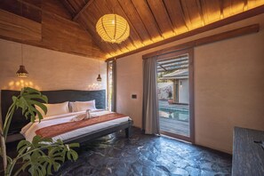 Een slaapkamer met een bed, een hanglamp, een potplant en uitzicht op buiten.