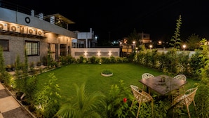 A modern house with a well-maintained lawn, outdoor seating, and a checkered pathway leading to the entrance. - Shubh Ashray (UDAIPUR)