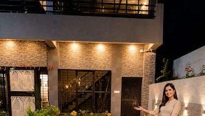 A checkered outdoor area with potted plants, a staircase, and a person standing. - Shubh Ashray (UDAIPUR)