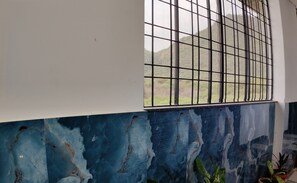A room with a window featuring metal bars, a white wall, and a blue painted lower section.